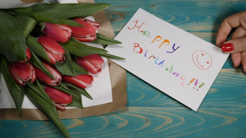 Happy birthday message note and tulips flowers bouquet on...